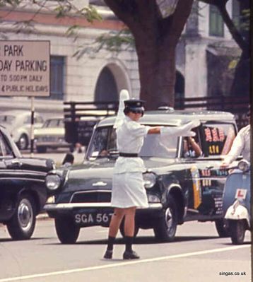 Female Cop
A Singapore policewoman.  Note the Anglia van, when did you last see one of those?
Keywords: policewoman;Cop;Anglia van