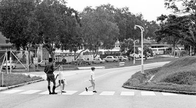 Portsdown Road at the end of the school day
Shows Portsdown Road at the end of the school day with a Malay soldier doing traffic control, and some of the 27 buses that came to pick up the widely scattered children of Pasir Panjang Junior School.
Keywords: Bill Johnston;Wessex Junior;Pasir Panjang Junior;School;Portsdown Road