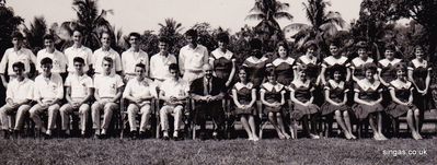 The Head master is in the centre with the ASM prefects
Official photograph, copyright to Henry Moon, 244 Orchard Road, Singapore.  The Head master is in the centre with the ASM prefects â€“ note all the boys are in long trousers.  It was taken not long before I went back to the UK.  Again I recognise all the faces, but names- how about YOU lot reading this give them to me?

ASM people â€“ what were the names, and colours of the four Knight of the Round Table â€“ Garwayn?, Lancelot, ? and ?.  The colours were red, blue, green and yellow.  I was in the yellow and wore a yellow badge with â€œPREFECTâ€ on it, a school badge Zulu shield shaped, and the athletics badge.  I still have the athletic and prefects badges.
