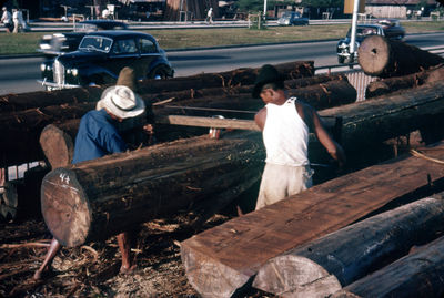Boat yard 1957
Teak logs being cut in a Boat yard using a tension saw.
