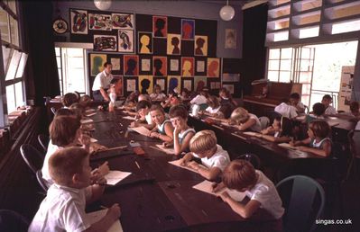 Another colour picture, of my classroom
Another colour picture, of my classroom on the first storey of the main block with me in traditional 'uniform'. These upper classrooms were cooler than those downstairs and mine had a little window at the other end through which I could show 35mm films from a projector in the adjoining store room. I borrowed films from the British Council
Keywords: Bill Johnston;Wessex Junior;Pasir Panjang Junior;School