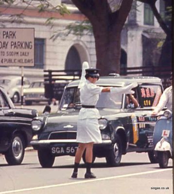 Female Cop
A Singapore policewoman.  Note the Anglia van, when did you last see one of those?
Keywords: policewoman;Cop;Anglia van