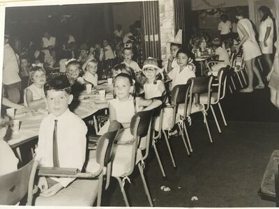 1969
Back from left to right with seats facing the camera: my friend Sally Anne Walker, myself with a small ponytail at the top of my hair and wearing a beautiful aqua dress with a white colour with embroidery, a boy in my class. Front second from left Deborah Mannion.
I do not remember any of the other children in the photo apart from the fact the girl 3rd from the left wearing a party hat had beautiful long red hair.
